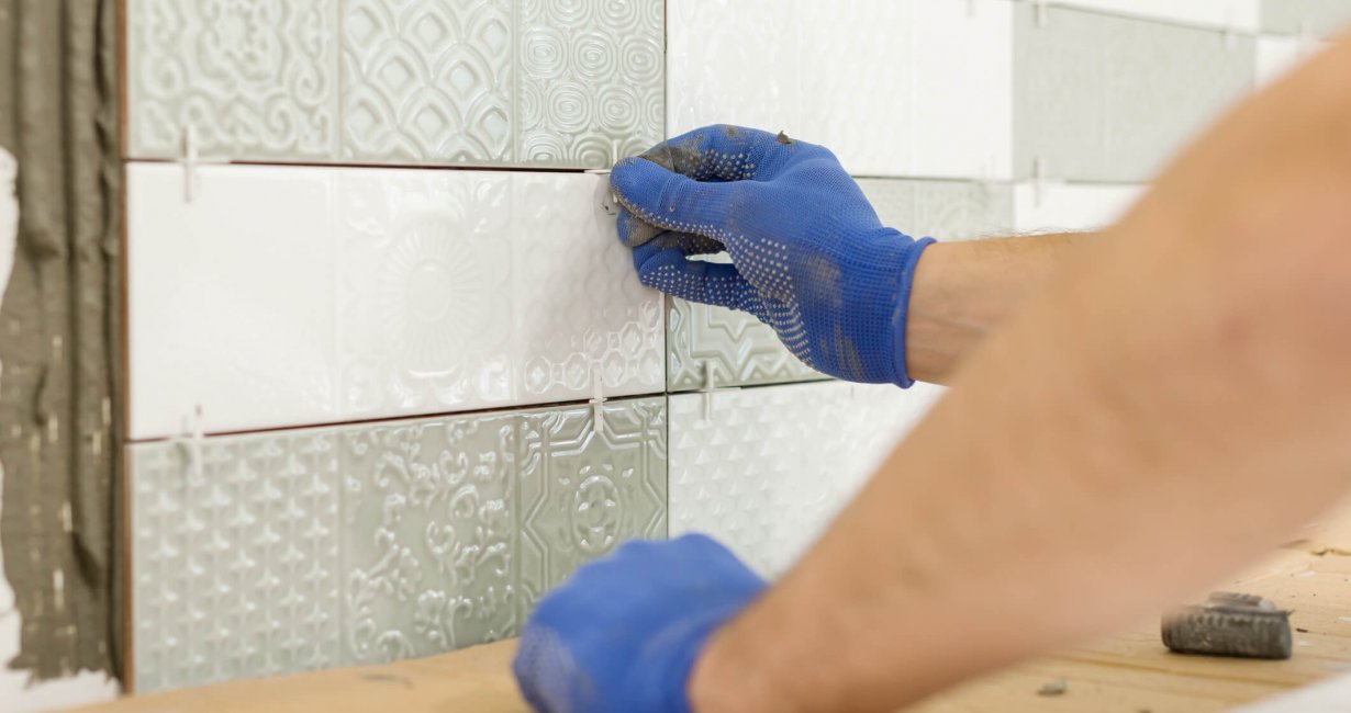 Installing ceramic tiles on the wall in kitchen. Placing tile spacers with hands, renovation, repair, construction